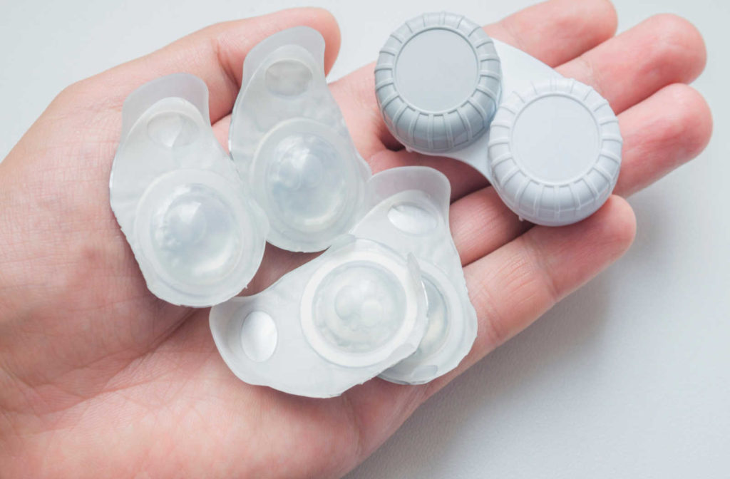 A hand holding contact lens blister packs and a contact lens case