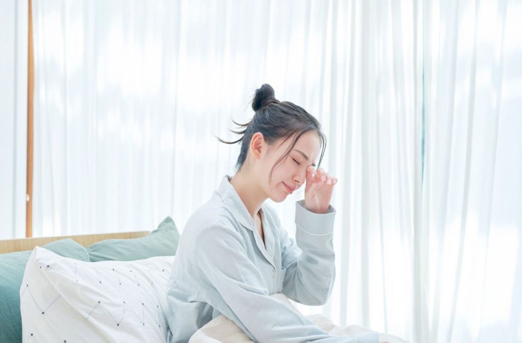 A woman waking up in the morning is rubbing her irritated dry eyes.