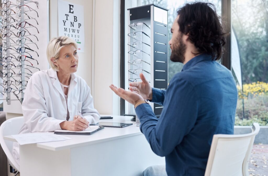 A young man explaining his symptoms to his optometrist to find out what's causing his blurry vision.