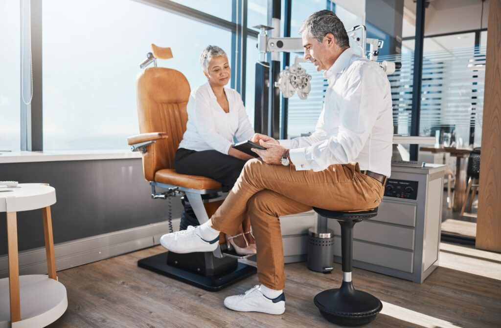 A woman sitting in a chair at the eye doctor's office, talking to her eye doctor about the risks of glaucoma.