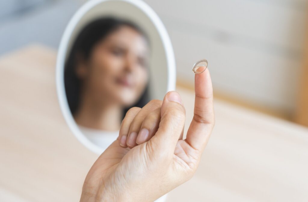 Close-up of a person's hand holding a contact lens on their finger.