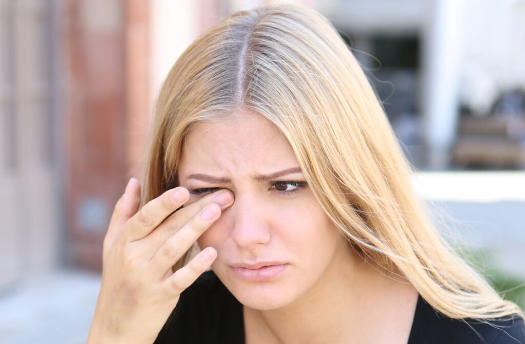 An adult rubs their eye when it feels like their contact lens is stuck and causing discomfort.