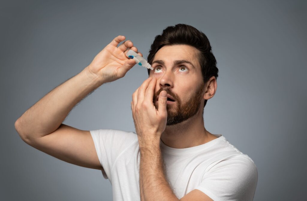 A person gently applying eye drops to target dryness.