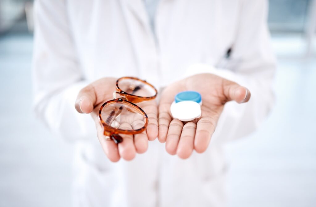 Two hands holding eyeglasses in one and a contact lens case in the other.